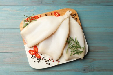 Photo of Uncooked squids with spices on blue wooden table, top view