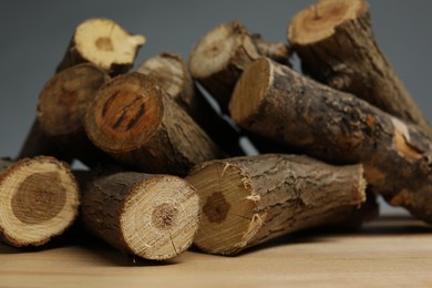 Photo of Pile of cut firewood on wooden table against grey background, closeup