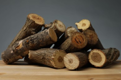 Photo of Pile of cut firewood on wooden table against grey background, closeup