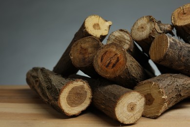 Photo of Pile of cut firewood on wooden table against grey background, closeup