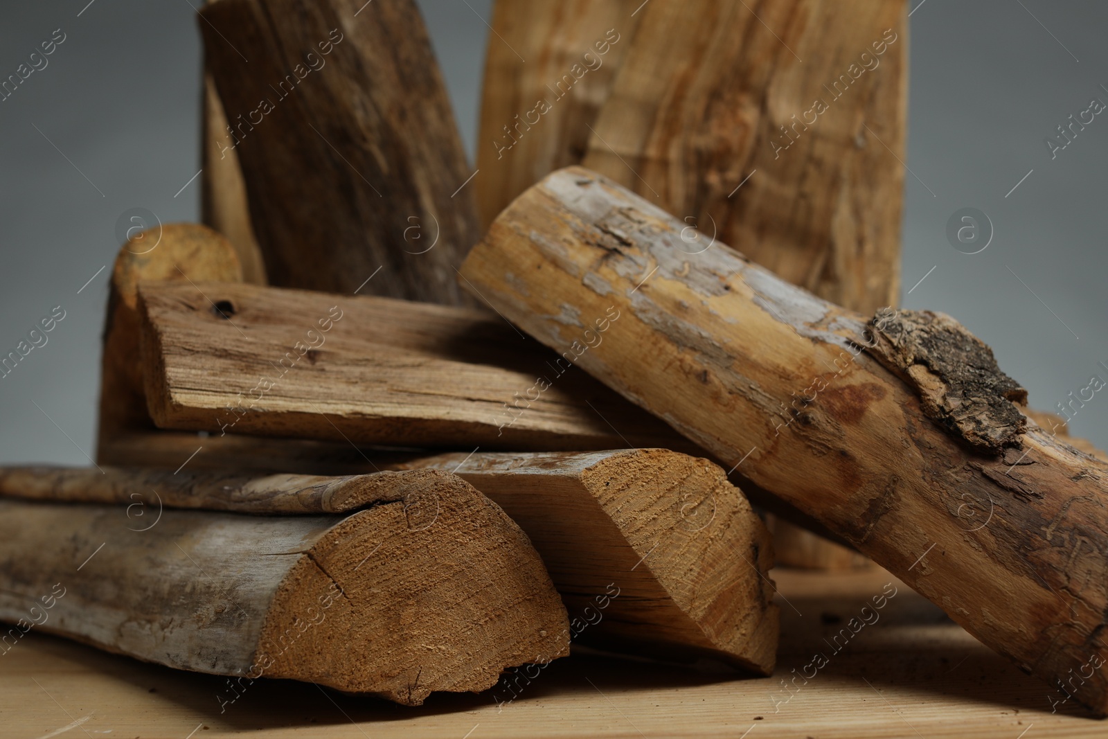 Pile of cut firewood on wooden table against grey background, closeup Photo of Pile of cut firewood on wooden table against grey background, closeup