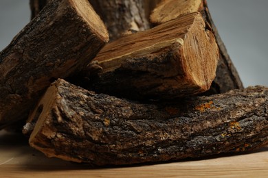 Photo of Pile of cut firewood on wooden table against grey background, closeup