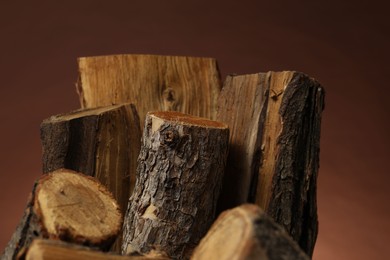 Photo of Pile of cut firewood on brown background, closeup