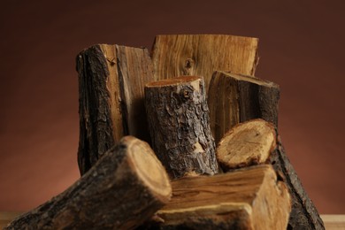 Photo of Pile of cut firewood on brown background, closeup