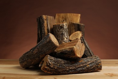 Photo of Pile of cut firewood on wooden table against brown background