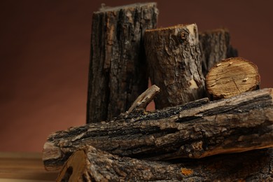 Photo of Pile of cut firewood on table against brown background, closeup