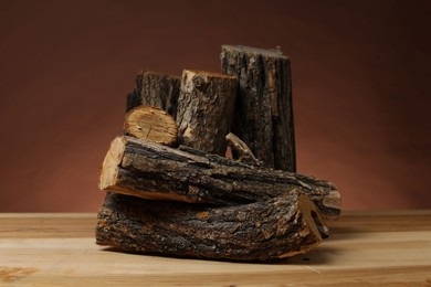 Photo of Pile of cut firewood on wooden table against brown background