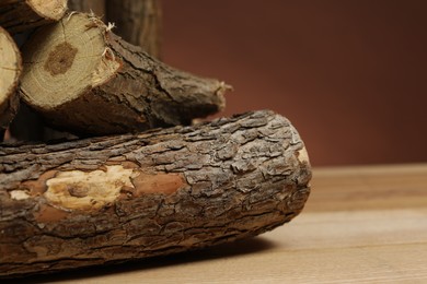 Photo of Pile of cut firewood on wooden table against brown background, closeup. Space for text