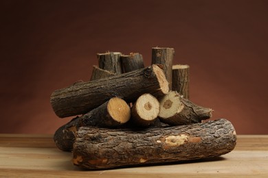 Photo of Pile of cut firewood on wooden table against brown background