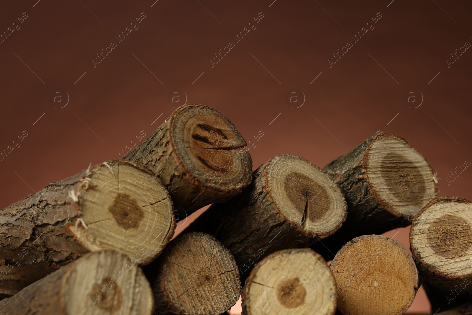 Photo of Pile of cut firewood on brown background, closeup
