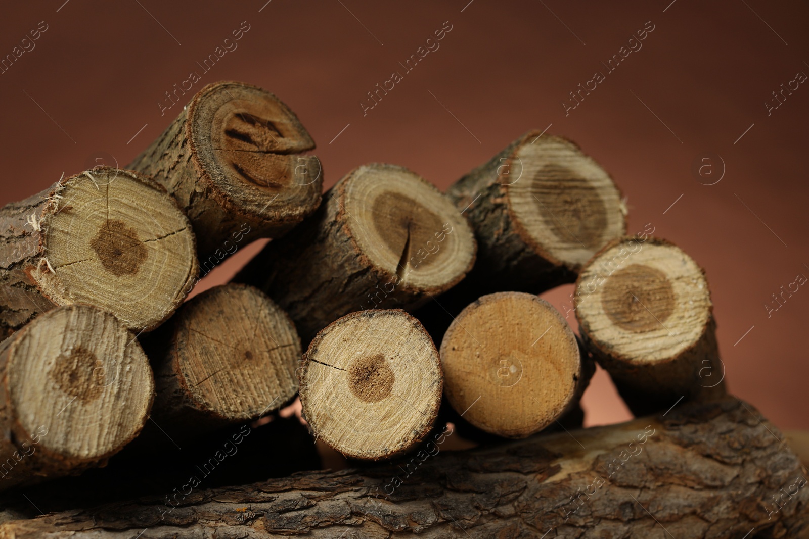 Photo of Pile of cut firewood on brown background, closeup