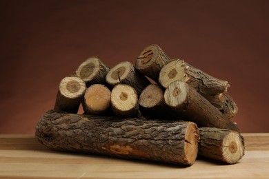 Photo of Pile of cut firewood on wooden table against brown background