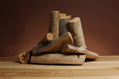 Photo of Pile of cut firewood on wooden table against brown background