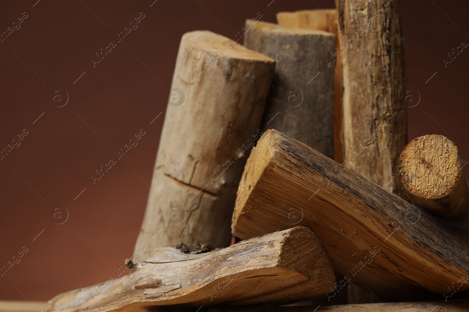Photo of Pile of cut firewood on brown background, closeup. Space for text