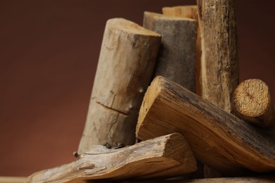 Photo of Pile of cut firewood on brown background, closeup. Space for text