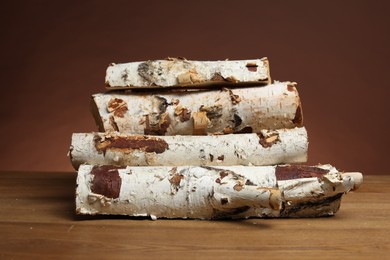 Photo of Pile of cut firewood on wooden table against brown background