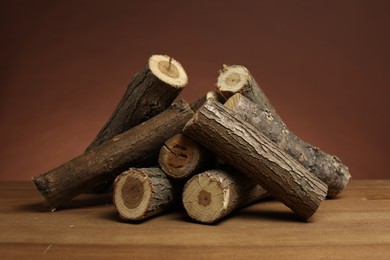 Photo of Pile of cut firewood on wooden table against brown background