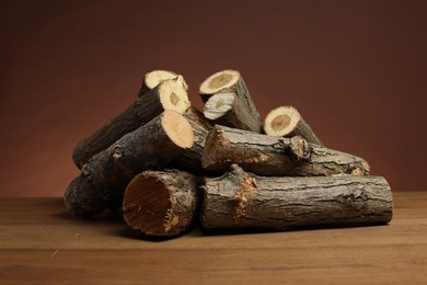 Photo of Pile of cut firewood on wooden table against brown background