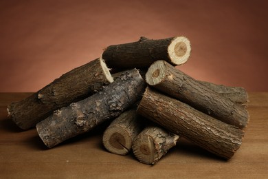 Photo of Pile of cut firewood on wooden table against brown background