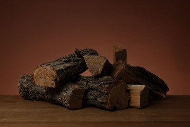 Photo of Pile of cut firewood on wooden table against brown background