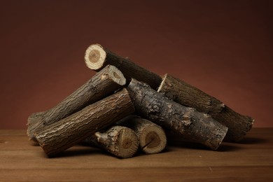 Photo of Pile of cut firewood on wooden table against brown background