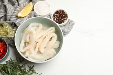 Photo of Uncooked squid rings and spices on white table, flat lay. Space for text
