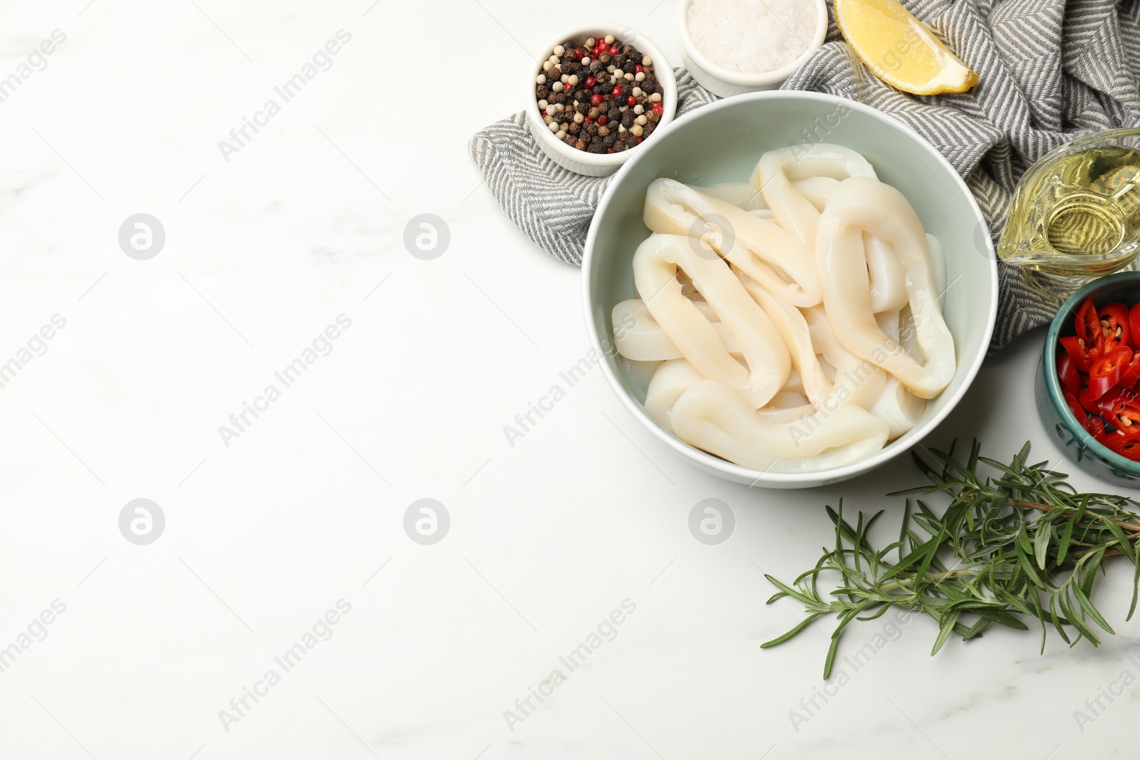 Photo of Uncooked squid rings and spices on white table, flat lay. Space for text