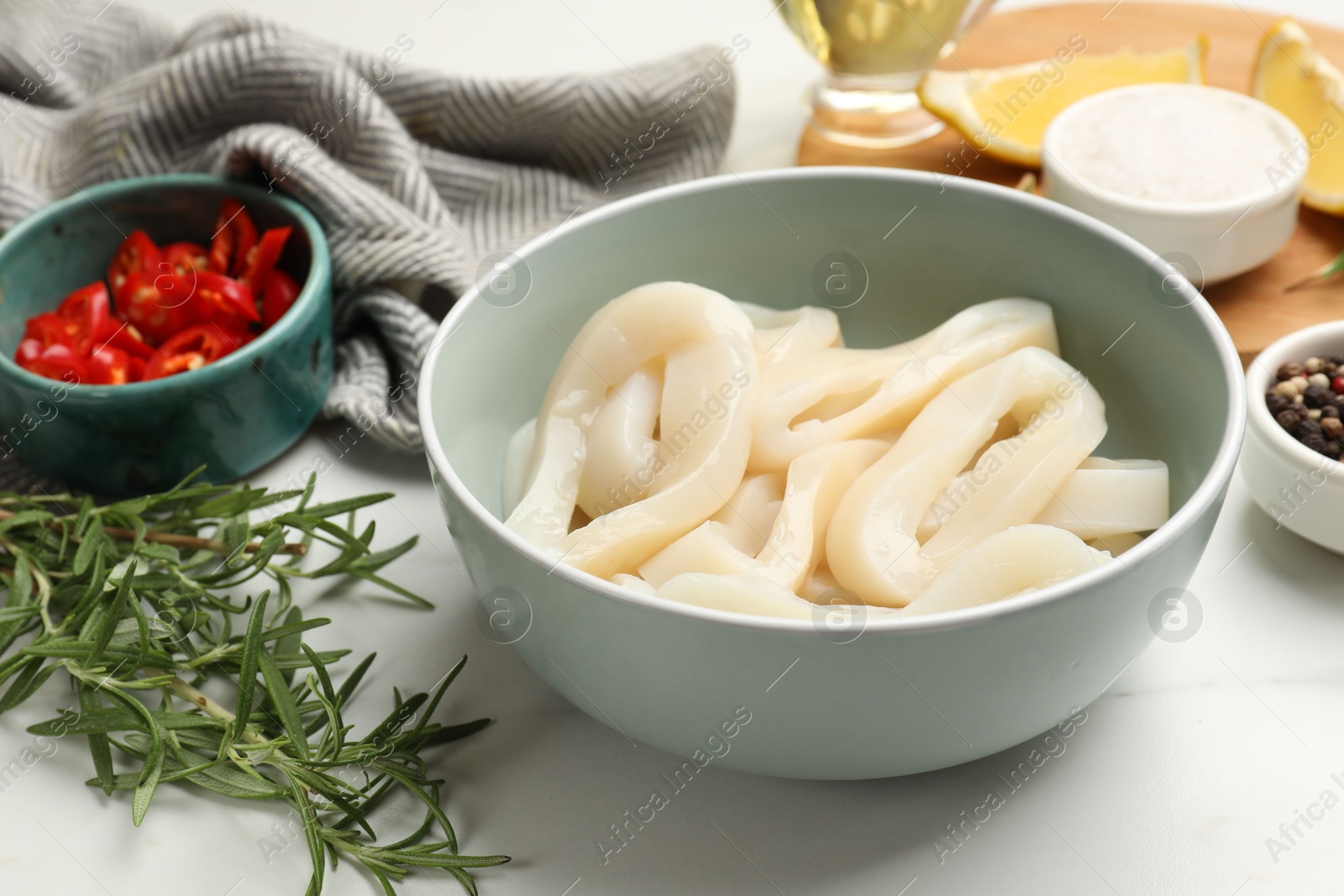Photo of Uncooked squid rings and spices on white table, closeup