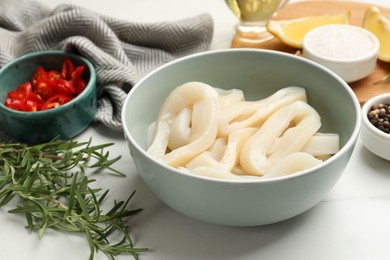 Photo of Uncooked squid rings and spices on white table, closeup