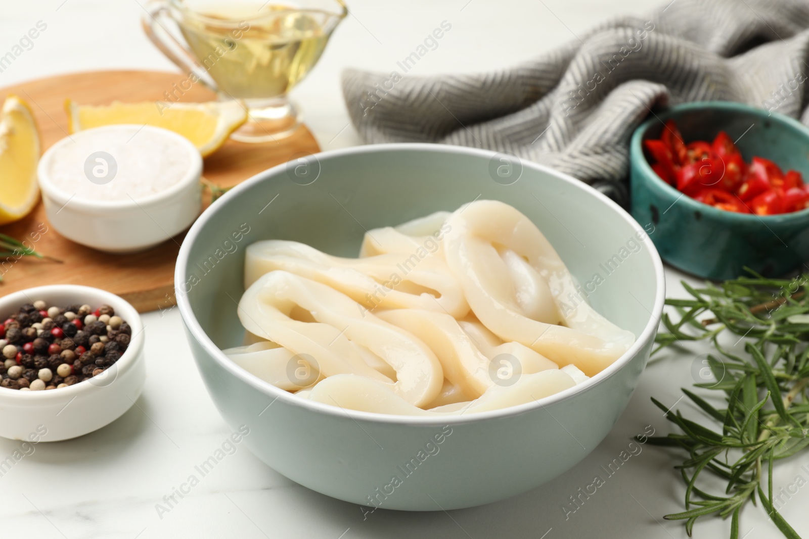 Photo of Uncooked squid rings and spices on white table, closeup