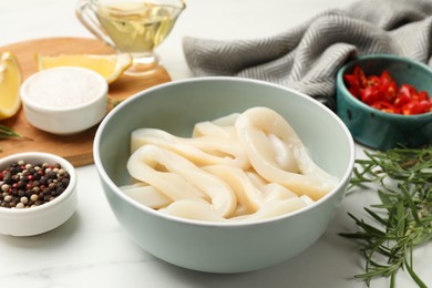Photo of Uncooked squid rings and spices on white table, closeup