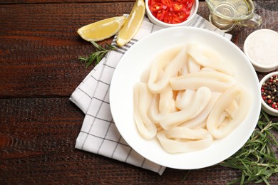 Photo of Uncooked squid rings and spices on wooden table, flat lay. Space for text