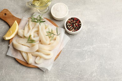 Photo of Uncooked squid rings and spices on grey table, flat lay. Space for text