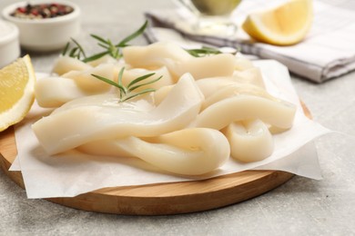 Photo of Uncooked squid rings and spices on grey table, closeup