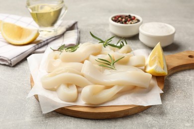 Photo of Uncooked squid rings and spices on grey table, closeup
