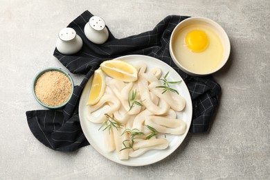 Photo of Uncooked squid rings and ingredients on grey table, flat lay