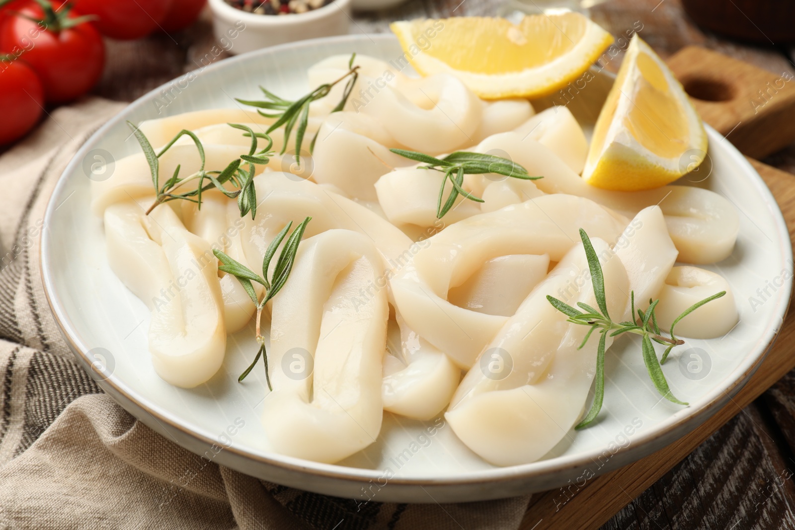 Photo of Uncooked squid rings, spices and tomatoes on table, closeup