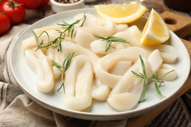 Photo of Uncooked squid rings, spices and tomatoes on table, closeup