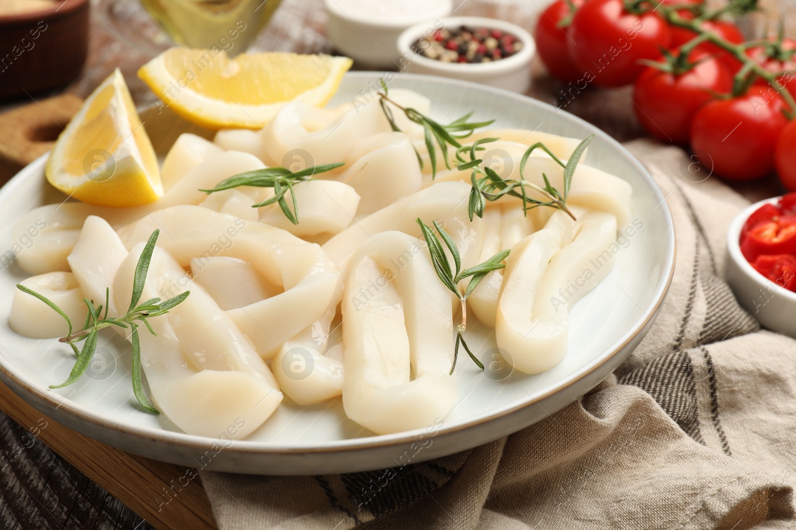 Photo of Uncooked squid rings, spices and tomatoes on table, closeup