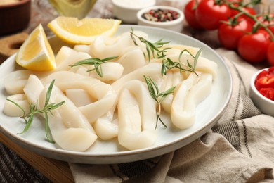 Photo of Uncooked squid rings, spices and tomatoes on table, closeup