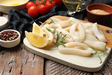 Photo of Uncooked squid rings, spices, yolk, tomatoes and bread crumbs on wooden table, closeup