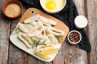 Photo of Uncooked squid rings, spices, yolk and bread crumbs on wooden table, flat lay