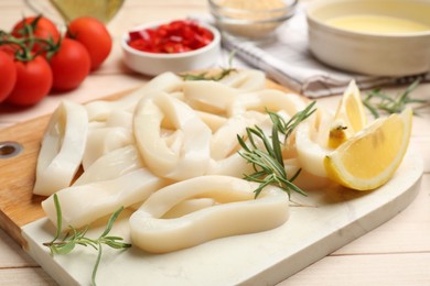 Photo of Uncooked squid rings, spices, yolk and tomatoes on wooden table, closeup
