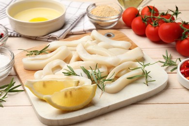 Photo of Uncooked squid rings, spices, yolk, tomatoes and bread crumbs on wooden table, closeup