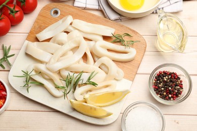 Photo of Uncooked squid rings, spices, yolk and tomatoes on wooden table, flat lay