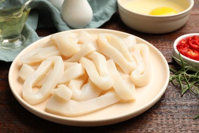 Photo of Uncooked squid rings, spices and yolk on wooden table, closeup