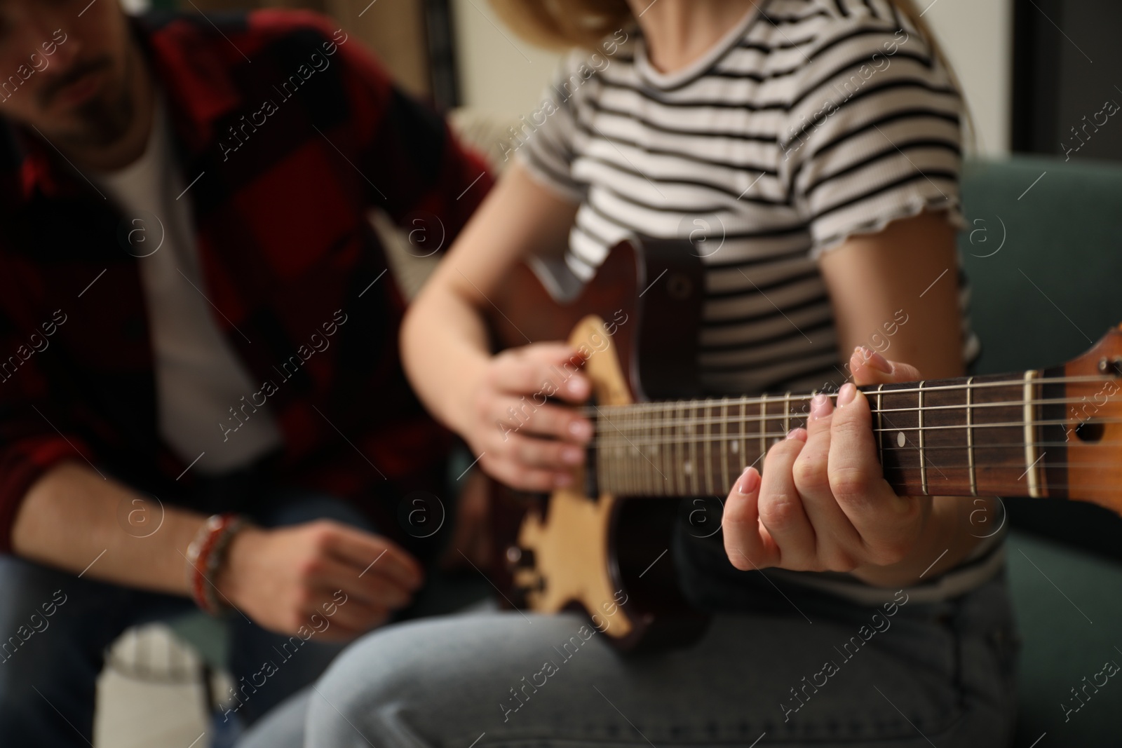 Photo of Tutor teaching woman to play guitar at home, closeup