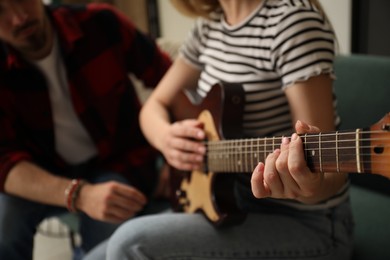 Photo of Tutor teaching woman to play guitar at home, closeup