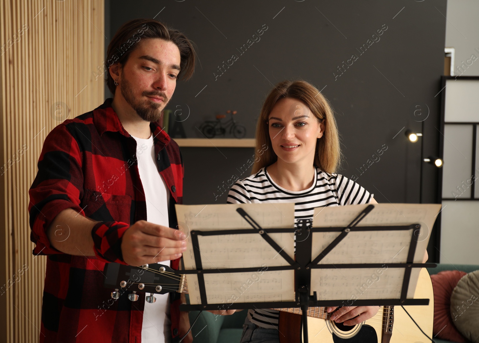 Photo of Tutor teaching woman to play guitar indoors