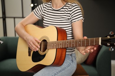 Photo of Woman learning to play guitar indoors, closeup